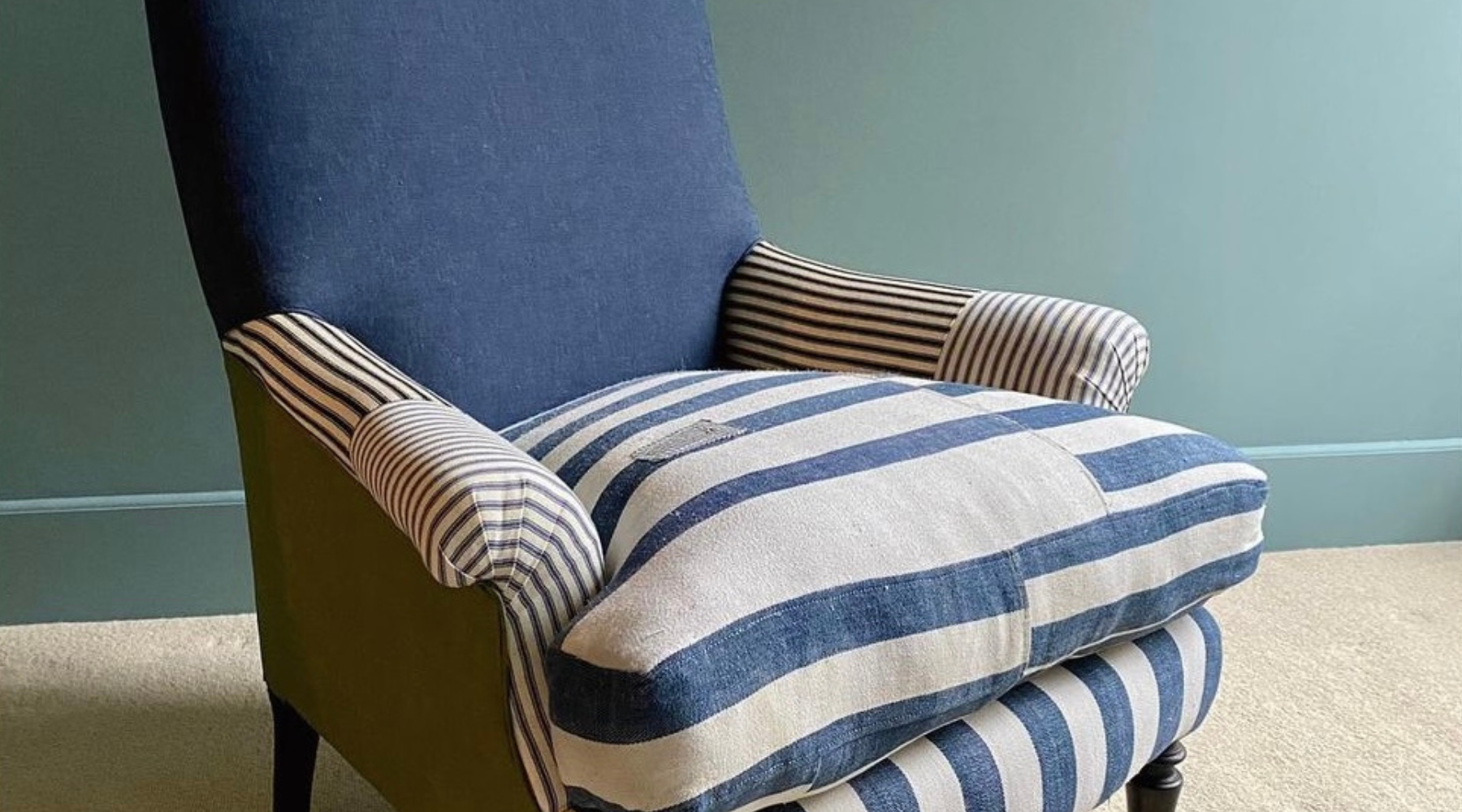 Blue and off-white colour striped chair. The back of the chair is a solid navy blue colour. The chair is facing the camera at an angle.